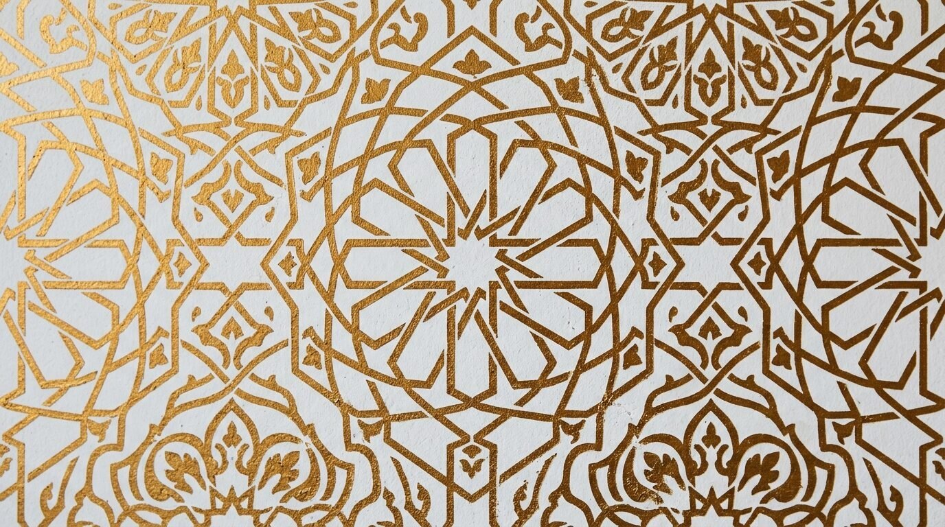 Close up of a metallic gold interlacing star and floral geometric design on a textured white surface.