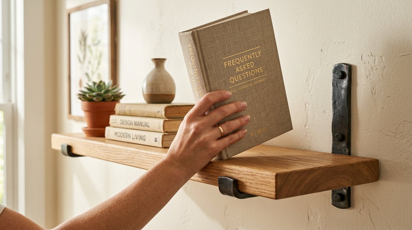 A person's hand with a gold ring setting a book titled Frequently Asked Questions onto a rustic oak wall shelf.