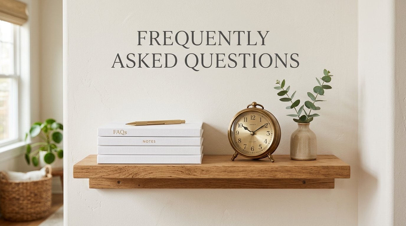 Floating wood shelf displaying white FAQ journals, a gold clock, and a small vase with eucalyptus on a beige wall.
